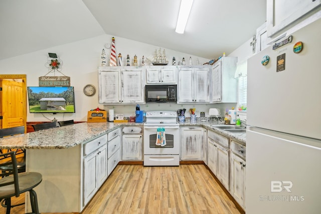 kitchen with white appliances, a peninsula, vaulted ceiling, light wood-style floors, and a breakfast bar area