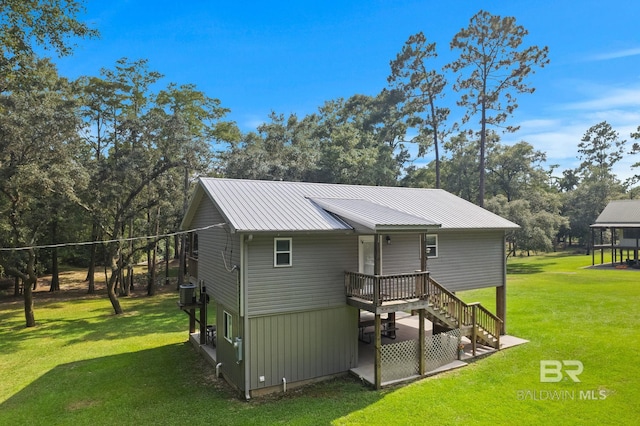 rear view of house featuring a lawn, metal roof, view of scattered trees, and central AC