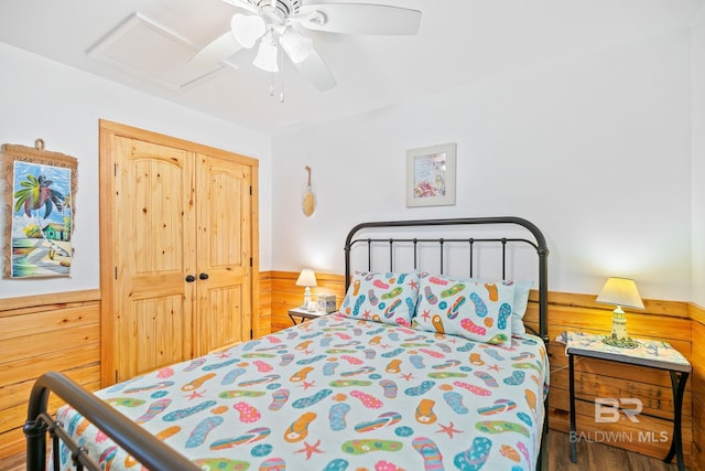 bedroom with attic access, a ceiling fan, a closet, and a wainscoted wall