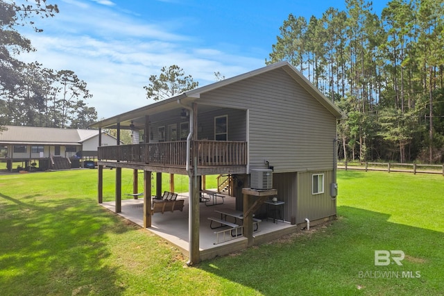 rear view of property with a wooden deck, a patio, central AC unit, and a yard