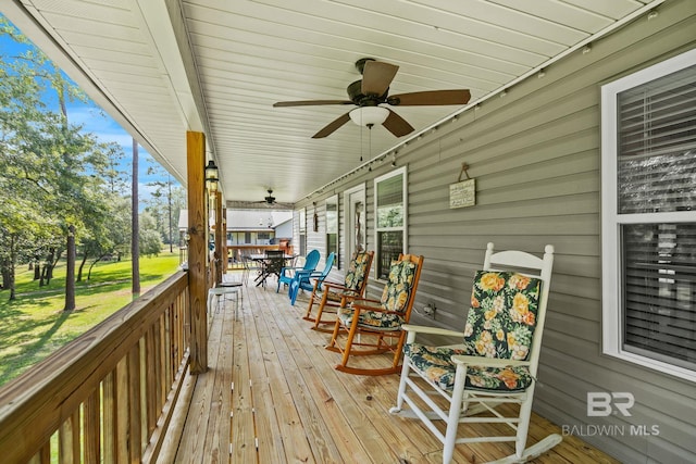 wooden deck with ceiling fan and a lawn