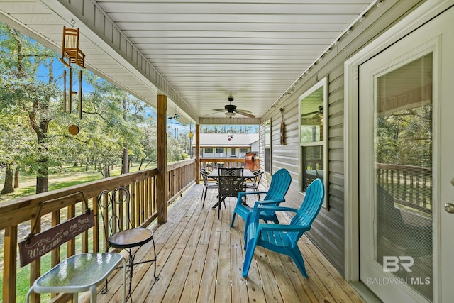 wooden deck featuring outdoor dining space and a ceiling fan