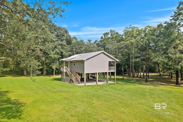 rear view of house featuring stairs, a lawn, a wooden deck, and a patio area