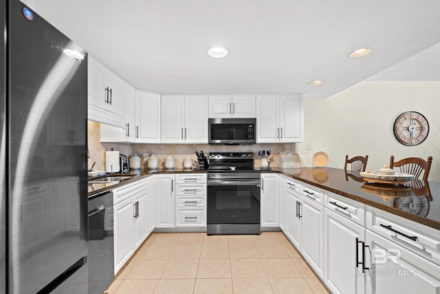 kitchen featuring backsplash, stainless steel appliances, light tile patterned floors, dark stone countertops, and white cabinetry