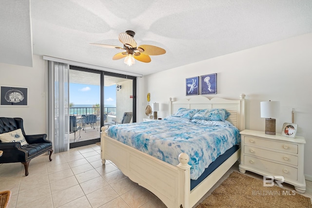 tiled bedroom with access to exterior, a textured ceiling, a wall of windows, and ceiling fan