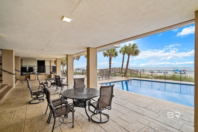 view of pool with a patio and a water view