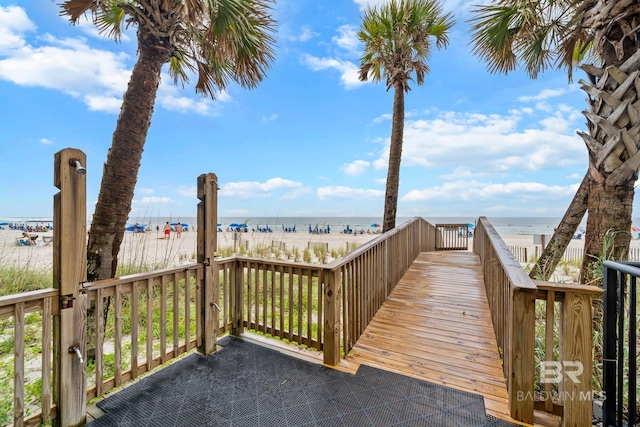 wooden terrace featuring a water view and a view of the beach