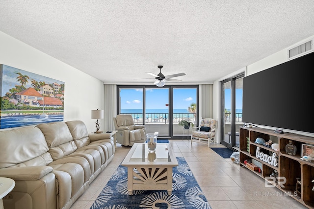 tiled living room with a textured ceiling, a wall of windows, and ceiling fan