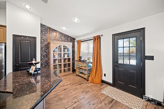 foyer featuring plenty of natural light, vaulted ceiling, and light hardwood / wood-style flooring