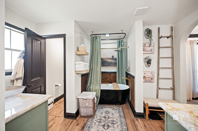 bathroom with a tub to relax in, hardwood / wood-style floors, and vanity