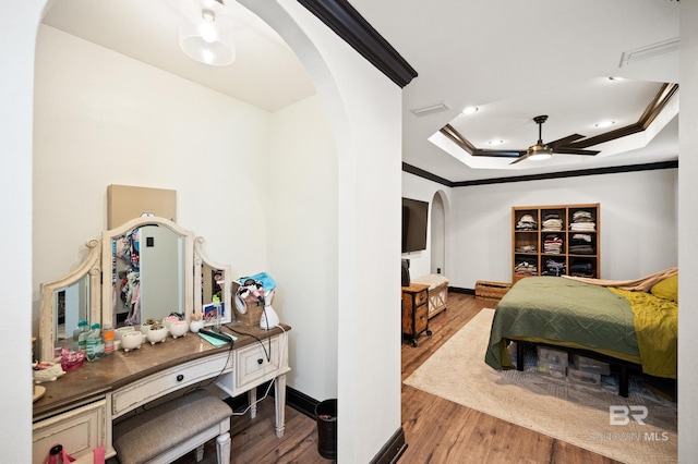 bedroom with a tray ceiling, wood-type flooring, and ornamental molding