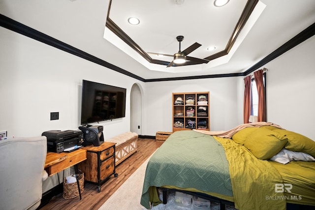 bedroom with a tray ceiling, ceiling fan, hardwood / wood-style floors, and ornamental molding