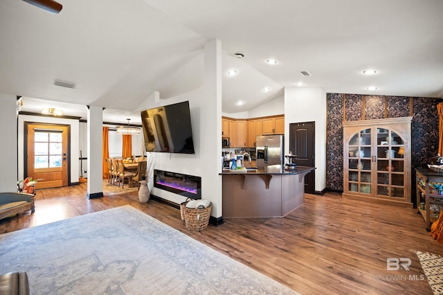 kitchen featuring sink, stainless steel appliances, lofted ceiling, a breakfast bar, and hardwood / wood-style flooring