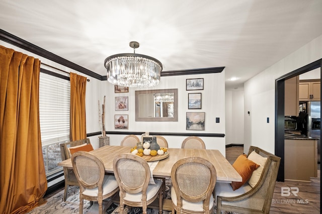 dining area with hardwood / wood-style floors, ornamental molding, and a chandelier