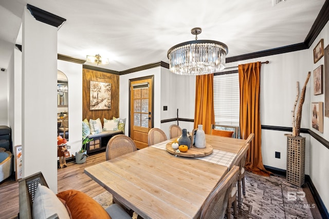 dining area featuring crown molding, an inviting chandelier, and hardwood / wood-style flooring