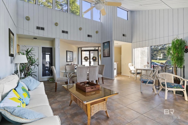 tiled living room featuring a wealth of natural light, ceiling fan, and a high ceiling