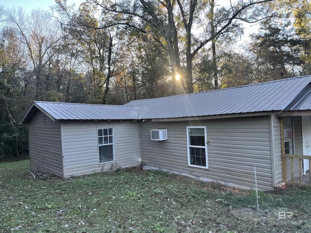 back of property with a wall mounted air conditioner and a yard