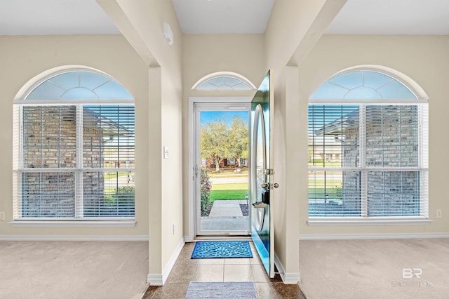 entrance foyer with tile patterned floors, baseboards, and carpet