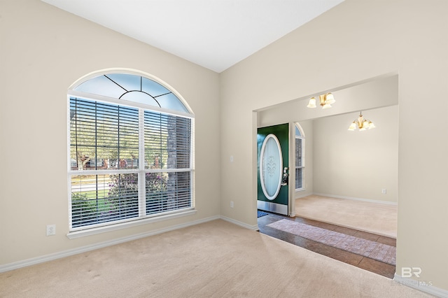 tiled entrance foyer with carpet floors, a notable chandelier, and plenty of natural light