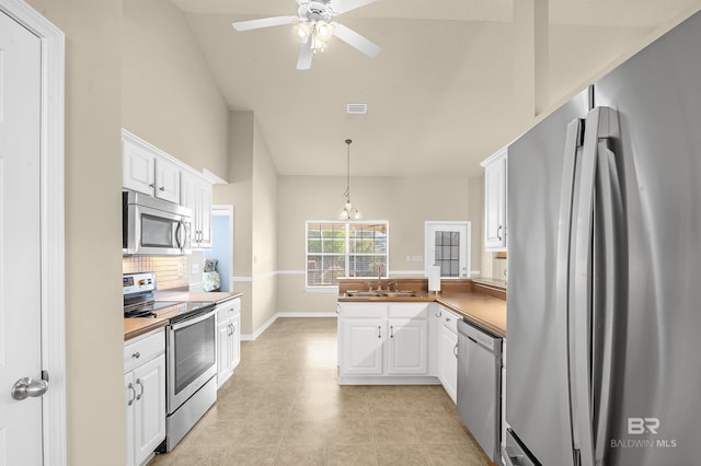 kitchen featuring ceiling fan, a peninsula, stainless steel appliances, white cabinetry, and a sink