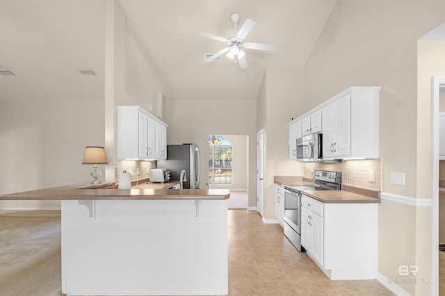 kitchen with visible vents, a kitchen bar, appliances with stainless steel finishes, a peninsula, and ceiling fan