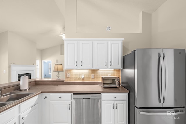 kitchen with backsplash, a toaster, vaulted ceiling, appliances with stainless steel finishes, and white cabinets