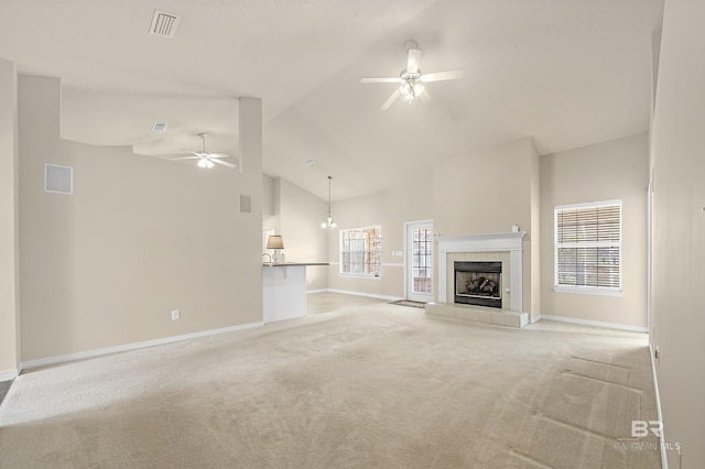 unfurnished living room with high vaulted ceiling, light colored carpet, a healthy amount of sunlight, and a ceiling fan