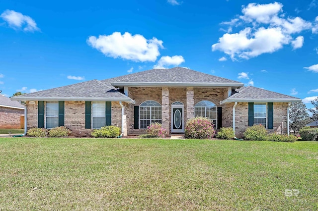 view of front of house featuring brick siding, roof with shingles, and a front lawn