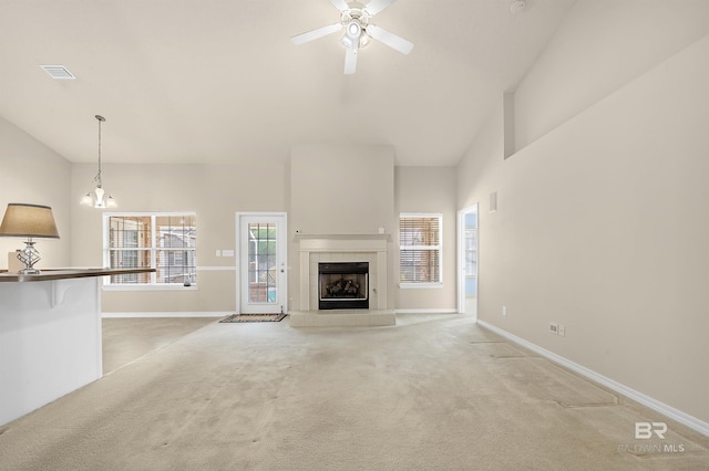 unfurnished living room featuring visible vents, light carpet, a tiled fireplace, baseboards, and ceiling fan