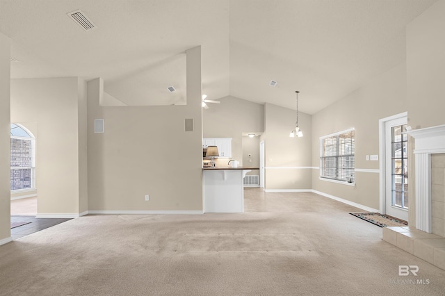 unfurnished living room with visible vents, light colored carpet, high vaulted ceiling, and ceiling fan with notable chandelier