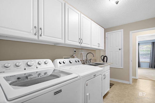 clothes washing area featuring a sink, a textured ceiling, cabinet space, separate washer and dryer, and light tile patterned floors