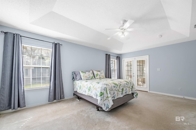 bedroom featuring a tray ceiling, multiple windows, and a textured ceiling