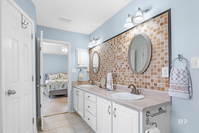 ensuite bathroom with a ceiling fan, visible vents, backsplash, and a sink