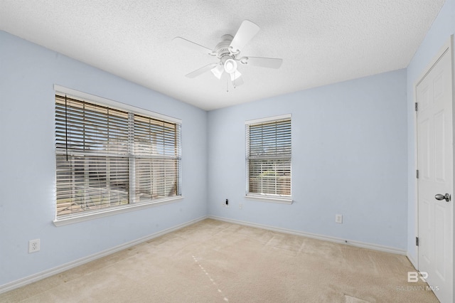 carpeted empty room with baseboards, a textured ceiling, and ceiling fan