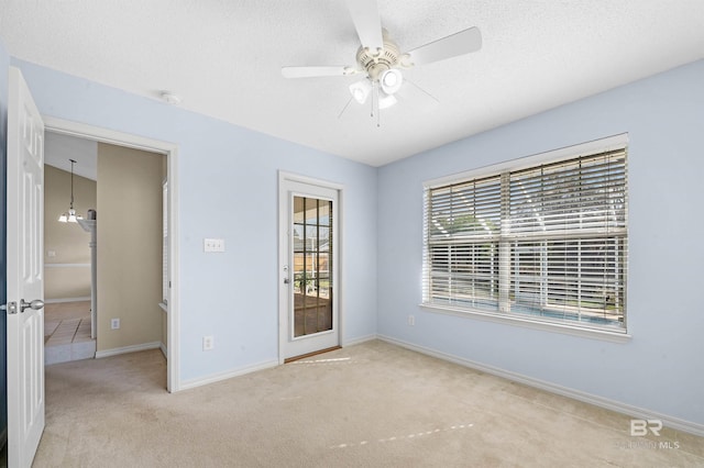 empty room featuring baseboards, a ceiling fan, carpet flooring, and a textured ceiling