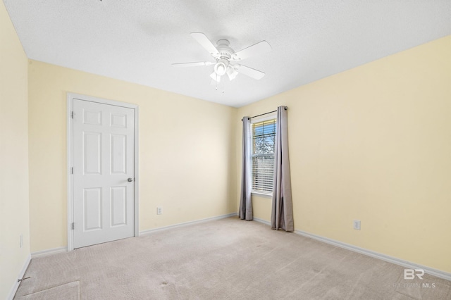 empty room featuring baseboards, light carpet, and a ceiling fan