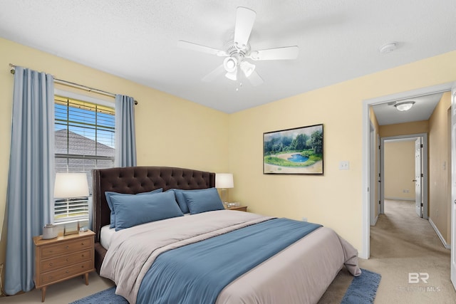 bedroom with light carpet, baseboards, a textured ceiling, and a ceiling fan