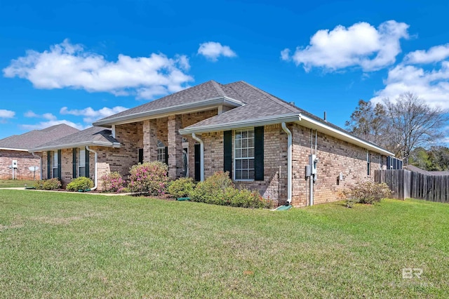 view of front of home featuring brick siding, a shingled roof, a front yard, and fence