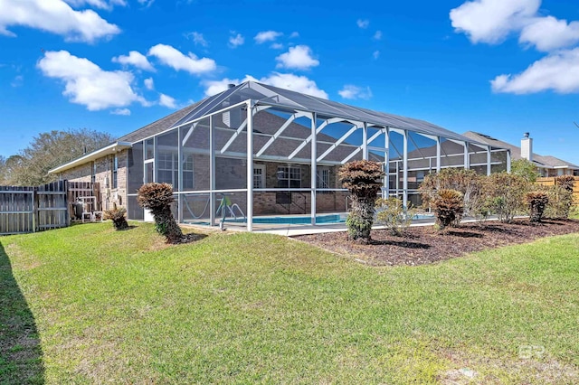 rear view of house with a lawn, glass enclosure, a fenced in pool, and fence