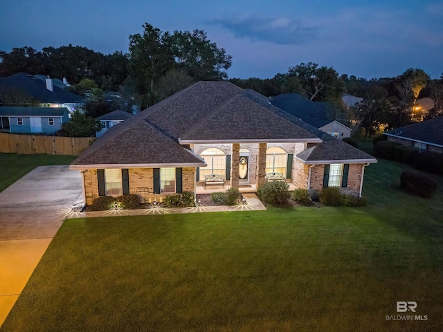 view of front of home featuring a front yard, fence, brick siding, and roof with shingles