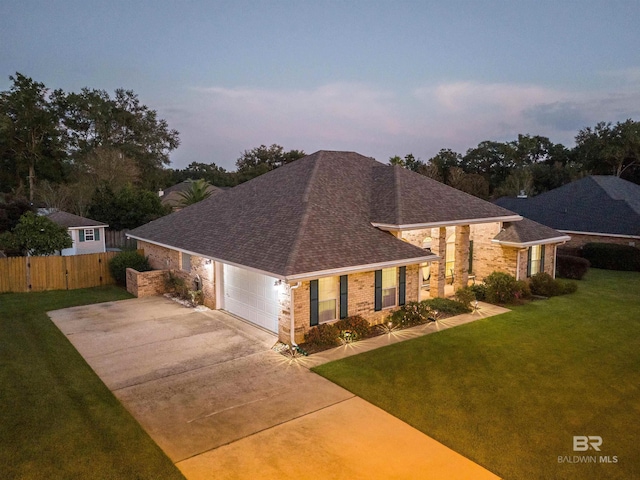 view of front of house with fence, a shingled roof, concrete driveway, a lawn, and brick siding