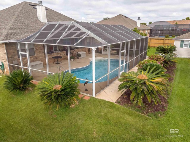 pool with a lanai, a yard, a patio area, and fence