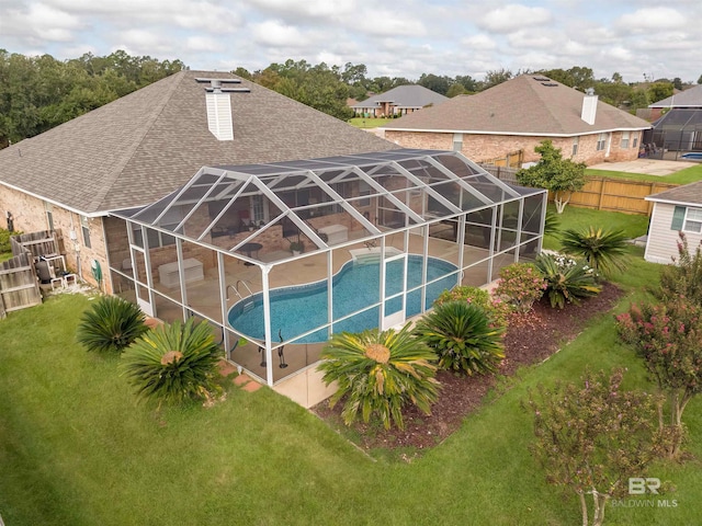 pool with glass enclosure, a patio, a fenced backyard, and a lawn