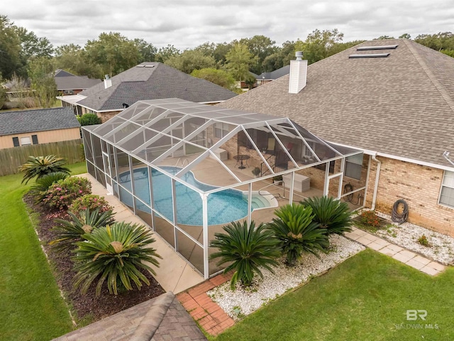 outdoor pool featuring a lanai, a patio area, and a lawn