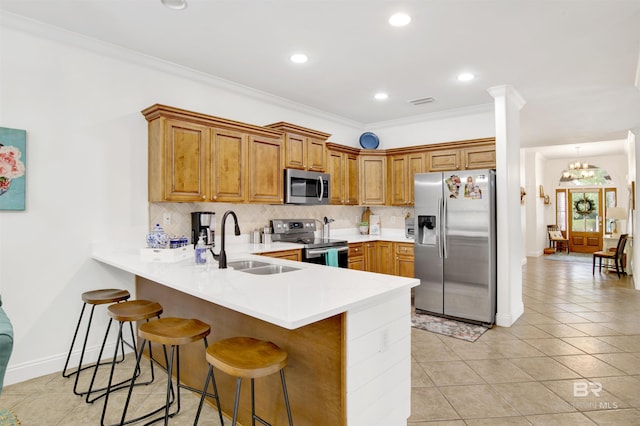 kitchen with a kitchen bar, sink, appliances with stainless steel finishes, kitchen peninsula, and decorative backsplash