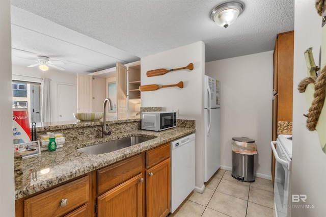 kitchen featuring white appliances, light stone countertops, sink, ceiling fan, and light tile patterned floors