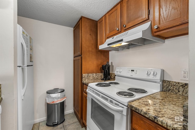 kitchen featuring a textured ceiling, dark stone counters, white appliances, and light tile patterned floors