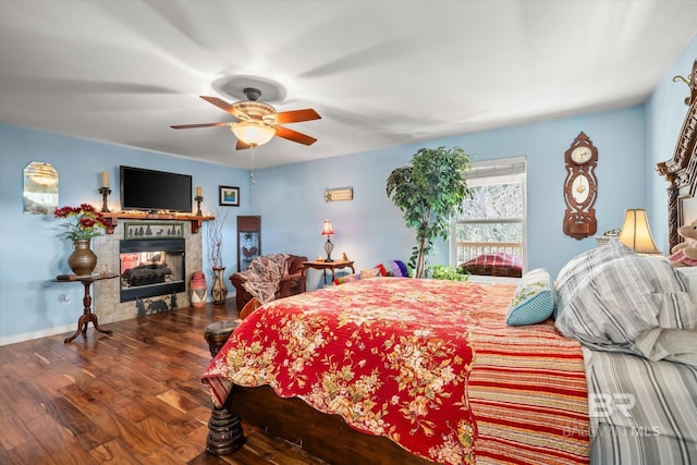 bedroom featuring a multi sided fireplace, ceiling fan, and dark hardwood / wood-style flooring