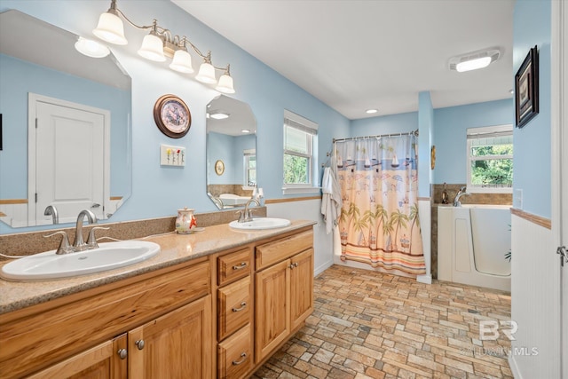 bathroom featuring vanity, a tub to relax in, and a healthy amount of sunlight