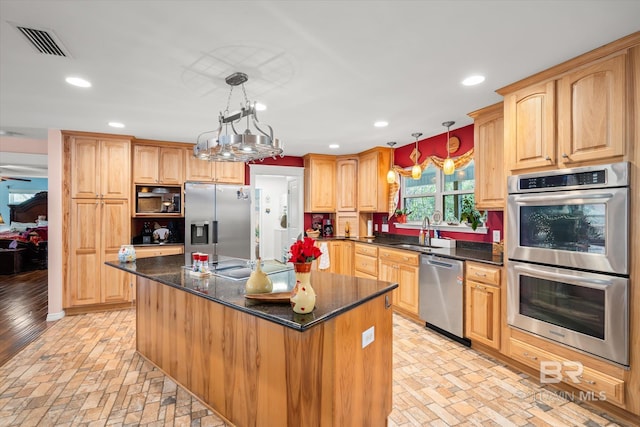 kitchen featuring sink, a kitchen island, hanging light fixtures, and appliances with stainless steel finishes